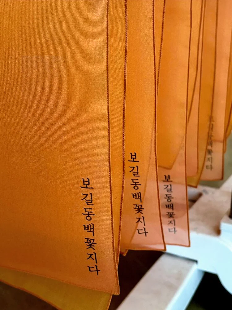 보길동백꽃지다 라고 적힌 주황 보자기들이 나란히 걸려 있는 모습