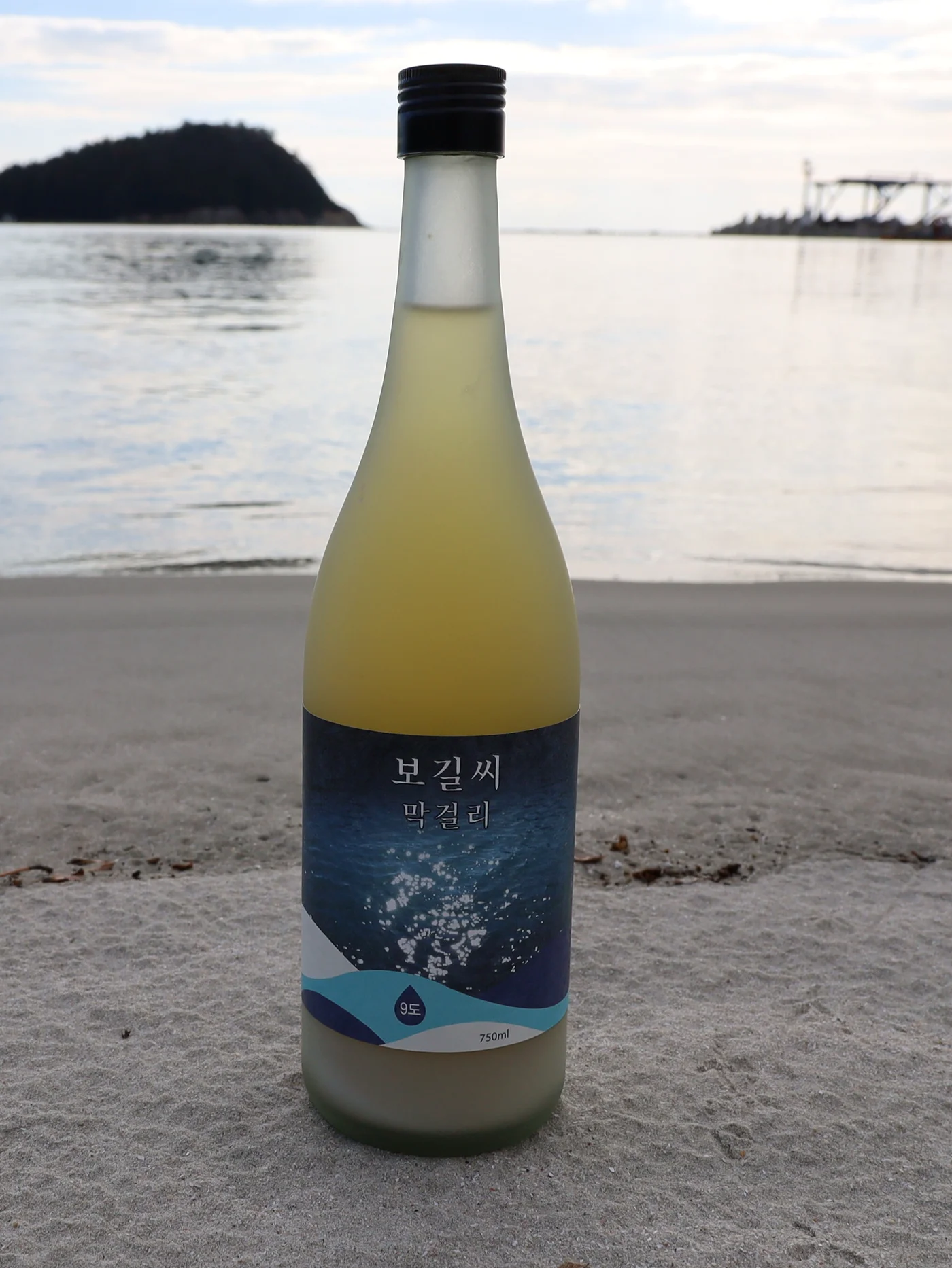보길도 해변에 놓인 보길씨막걸리 병, 파도 라벨과 9도 표기